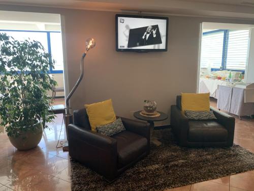 a living room with two chairs and a tv on the wall at Gabbiano Hotel in Civitanova Marche