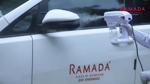 a person is standing next to a white truck at Ramada Plaza by Wyndham JHV Varanasi in Varanasi