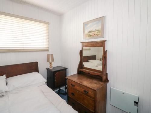 a bedroom with a bed and a mirror on a dresser at Driftwood in Wadebridge