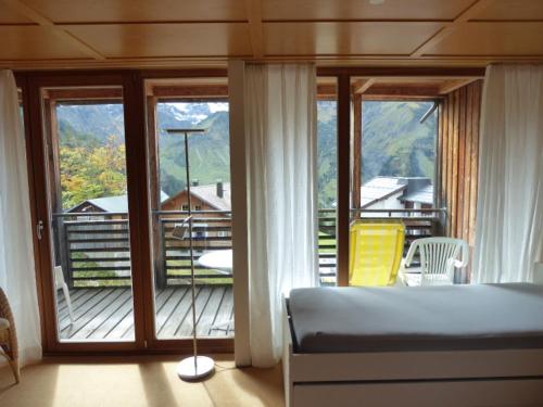 a bedroom with a bed and a view of a balcony at Widderstein Apartments in Schröcken
