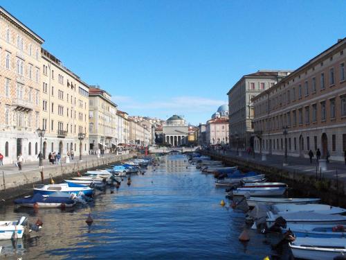 uma linha de barcos em um canal em uma cidade em Seven Historical Suites em Trieste