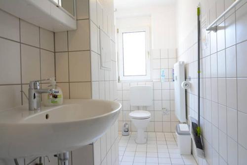 a white bathroom with a sink and a toilet at Private rooms next to subway in Nürnberg