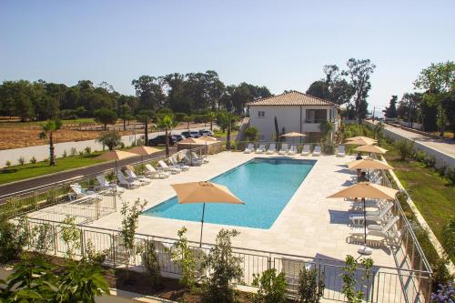 - une vue sur la piscine bordée de parasols et de chaises dans l'établissement A SUARA LINDA, à Ghisonaccia