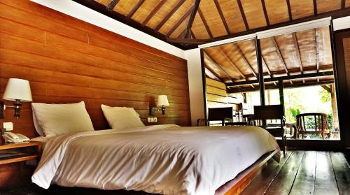 a bedroom with a large bed and a wooden wall at Tirta Arsanta Hot Springs & Villa in Bogor