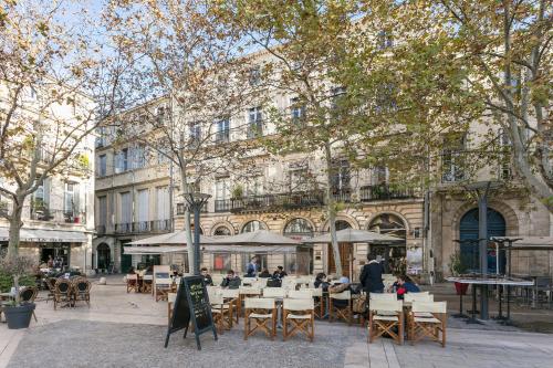 un café en plein air avec des tables et des chaises en face d'un bâtiment dans l'établissement LGC Habitat - Studios Hyper Centre, à Montpellier