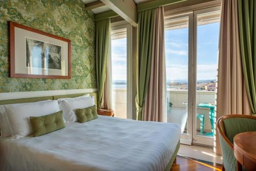 a bedroom with a bed and a large window at Grand Hotel Ortigia in Siracusa