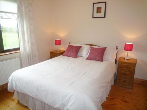1 dormitorio con 1 cama blanca grande y 2 lámparas en Boherbue Holiday Home, en Boherboy