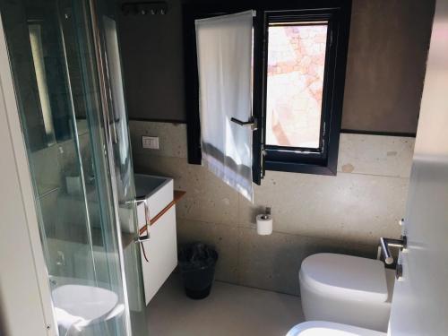 ein Bad mit einem WC, einem Waschbecken und einem Fenster in der Unterkunft Rena Village in Rena Majore
