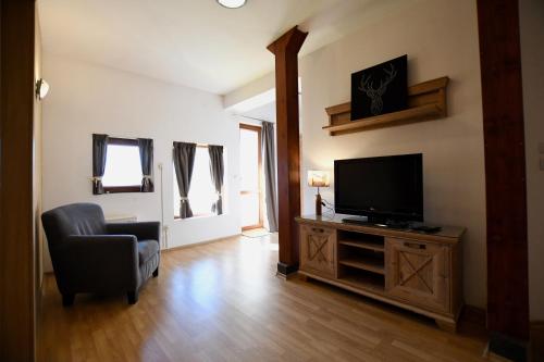 a living room with a television and a chair at Dolomiti Apartments in Bansko