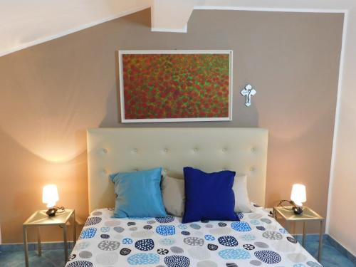 a bedroom with a bed with blue pillows and a painting at Case Vacanza Elisir in Favignana