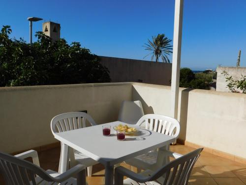 a white table with chairs and a plate of food on a balcony at Case Vacanza Elisir in Favignana