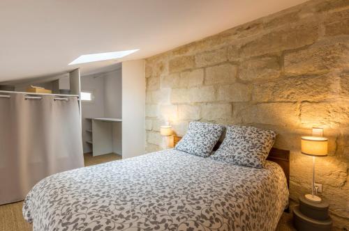une chambre avec un grand lit et un mur en pierre dans l'établissement La Parenthèse Roucher Montpellier - Duplex Climatisé T2 Cœur écusson MEUBLE TOURSIME 3 ETOILES, à Montpellier