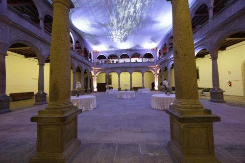 a large hall with tables and a chandelier at San Francisco Hotel Monumento in Santiago de Compostela