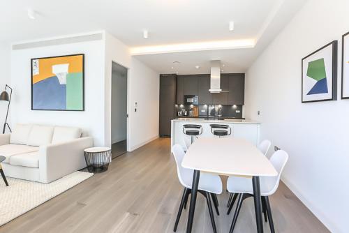 uma cozinha e sala de estar com uma mesa branca e cadeiras em The Eight Apartments Shoreditch em Londres