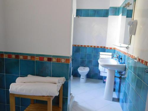 a blue tiled bathroom with a sink and a toilet at Case Vacanza Elisir in Favignana