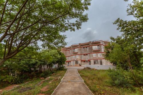 an old brick building with trees in front of it at KSTDC Hotel Mayura Krishna Almatti in Bāgalkot