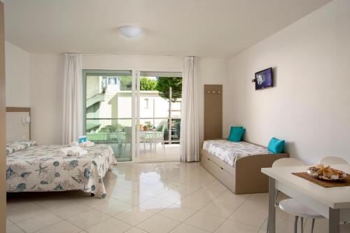 a bedroom with two beds and a table and a balcony at Residence I Diamanti - Siroli Collection in Cervia