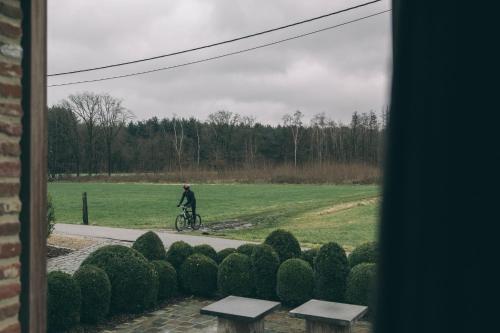 Herselt的住宿－B&B de ZIL，骑着自行车在田野上走上道路的人