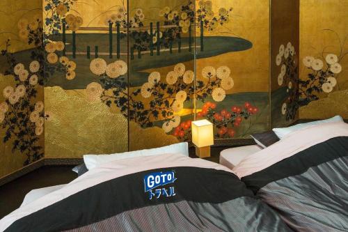 a bedroom with two beds and a painting on the wall at 京都二条城近く京町屋120年の歴史に泊まる in Kyoto