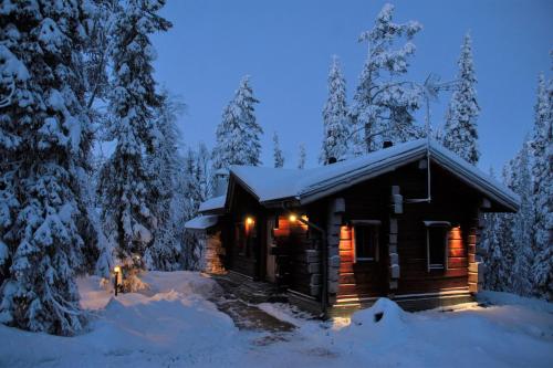 uma cabana de madeira na neve à noite em Taigakolo, Luosto em Luosto