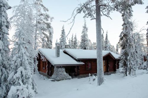 uma cabana de madeira na floresta com árvores cobertas de neve em Taigakolo, Luosto em Luosto