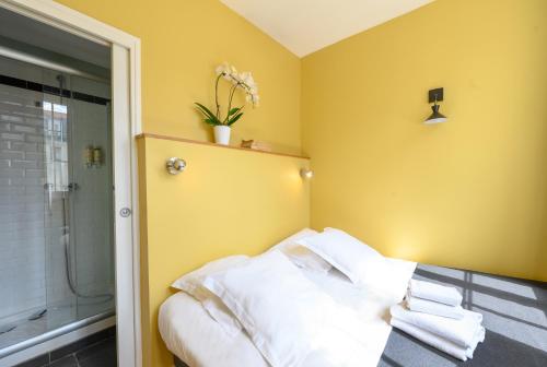 ein Schlafzimmer mit gelben Wänden und einem Bett mit weißen Kissen in der Unterkunft Suites & Hôtel Helzear Montparnasse in Paris