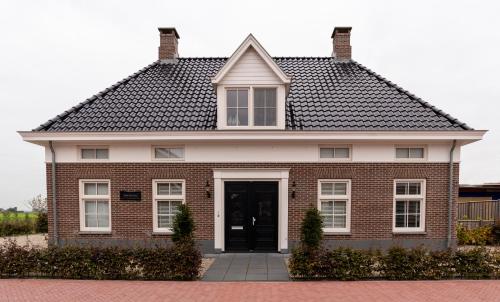 a red brick house with a black roof at Dinie's Bed en Brood in 's-Heerenbroek
