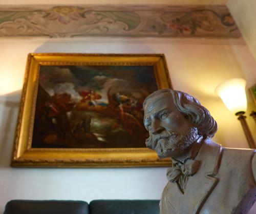 a painting of a man sitting in a chair at Hotel Verdi Boutique Hotel in Parma