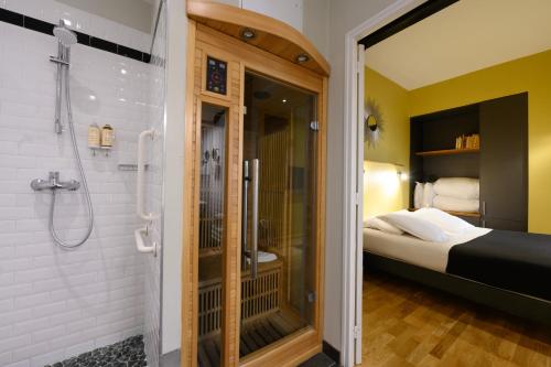 a bathroom with a shower and a bed in it at Suites & Hôtel Helzear Montparnasse in Paris