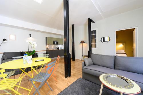 a living room with a couch and a table at Suites & Hôtel Helzear Montparnasse in Paris