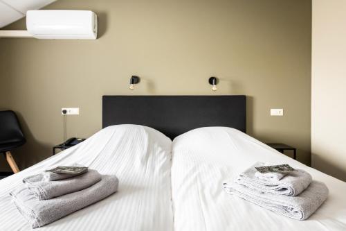 Una cama blanca con toallas encima. en De Drie Linden, en Luyksgestel