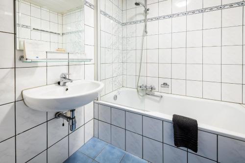 y baño blanco con lavabo y bañera. en De Drie Linden, en Luyksgestel