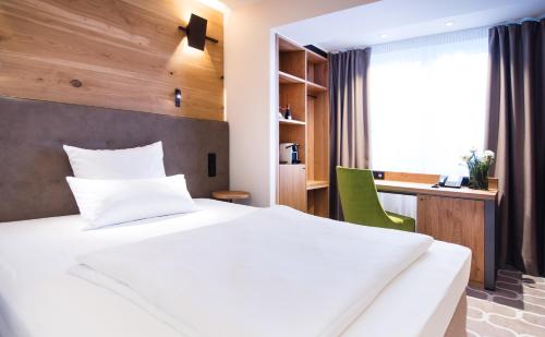 a hotel room with a large bed and a desk at Olymp Munich in Eching