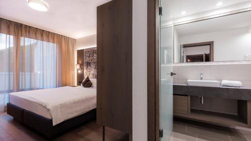 a bedroom with a bed and a sink and a mirror at Residenz Fliana Deluxe in Mathon