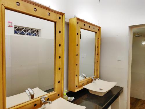 a bathroom with two sinks and two mirrors at Bedrock Boutique Hostel in Baga