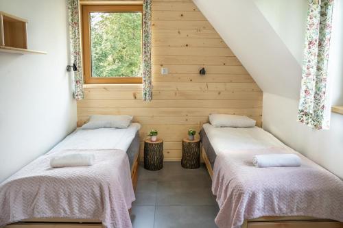 two beds in a small room with a window at Dziadek Władek in Zakopane