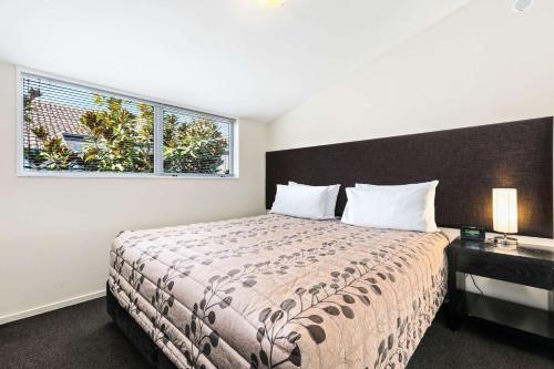 una camera con un grande letto e una finestra di Quality Suites Amore a Christchurch