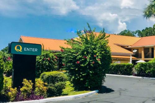 a sign in front of a hotel with a bush at Quality Inn near Manatee Springs State Park in Chiefland