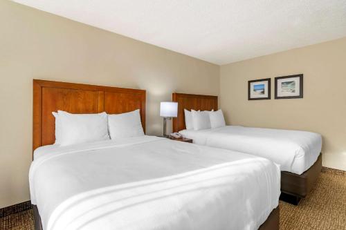 two beds in a hotel room with white sheets at Comfort Inn & Suites St Pete - Clearwater International Airport in Clearwater