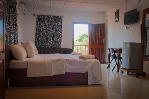 a bedroom with a bed and a television and a window at Paloma Guest House in Kenema