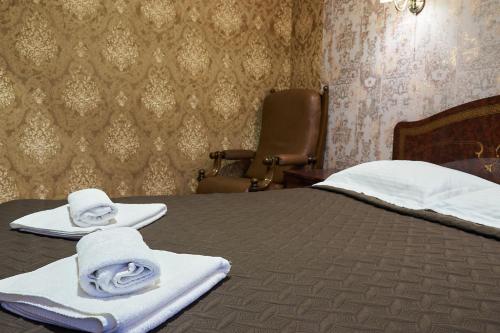 a bedroom with a bed with towels and a chair at Hotel Royal (Отель Роял) in Poltava