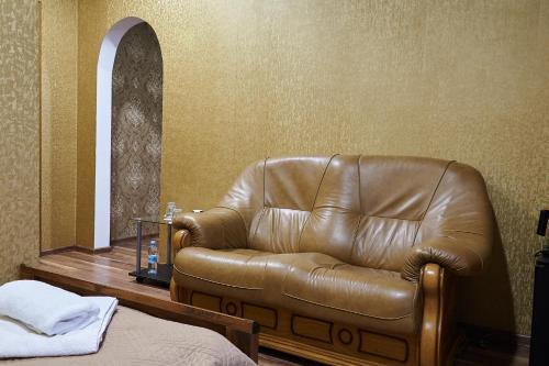 a brown leather couch in a room with a bed at Hotel Royal (Отель Роял) in Poltava