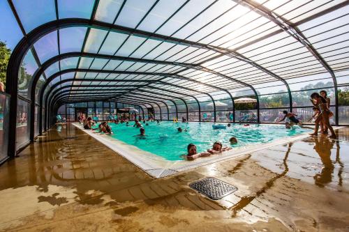 una gran piscina con gente en el agua en Mobil Home XXL 4 chambres - Camping Le Domaine de Bréhadour, en Guérande