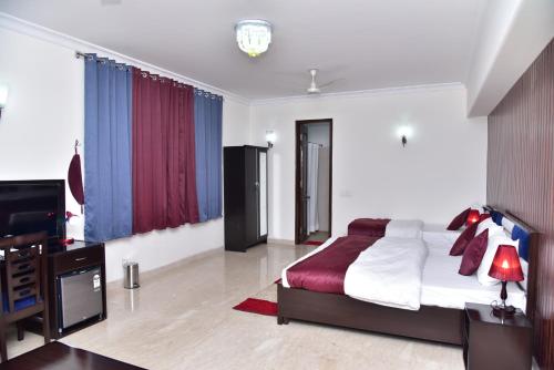 a bedroom with a bed and a desk and a television at Nook Inn & Suites - MG ROAD METRO in Gurgaon