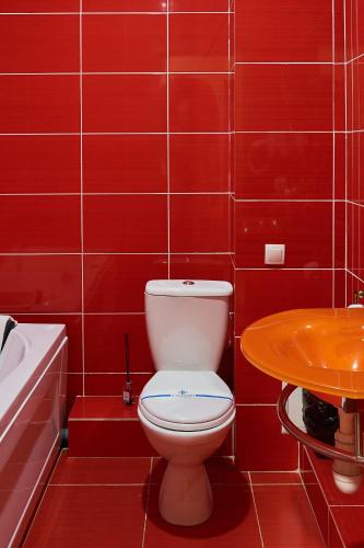 a red tiled bathroom with a toilet and a sink at Hotel Royal (Отель Роял) in Poltava