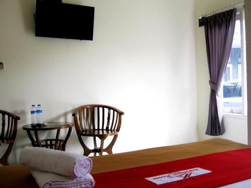 a room with a bed and two chairs and a television at Aqilakost Gadog Puncak Bogor in Bogor