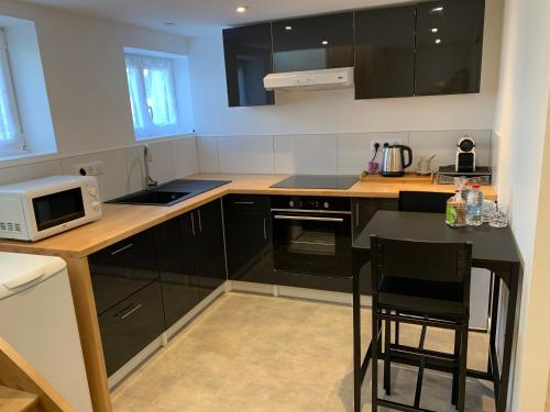 - une cuisine avec des armoires noires et un four micro-ondes blanc dans l'établissement Chalet TOUSVENTS, à Saint-Georges-de-Didonne