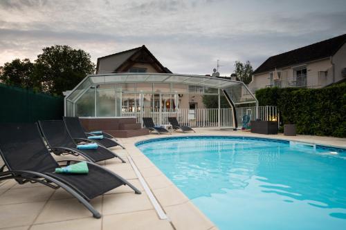 basen z leżakami obok domu w obiekcie Logis Hotel Restaurant L'Escapade w mieście Le Pêchereau