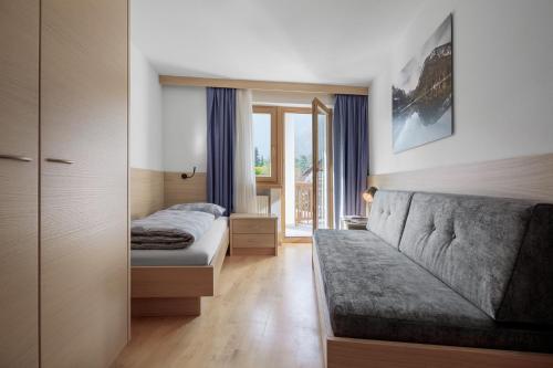 a bedroom with a couch and a bed and a window at DACIASA Apartment in San Vigilio Di Marebbe