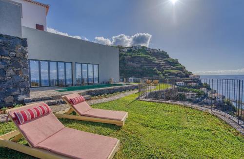 two lounge chairs sitting on the grass in front of a house at Socalco Nature Calheta in Calheta